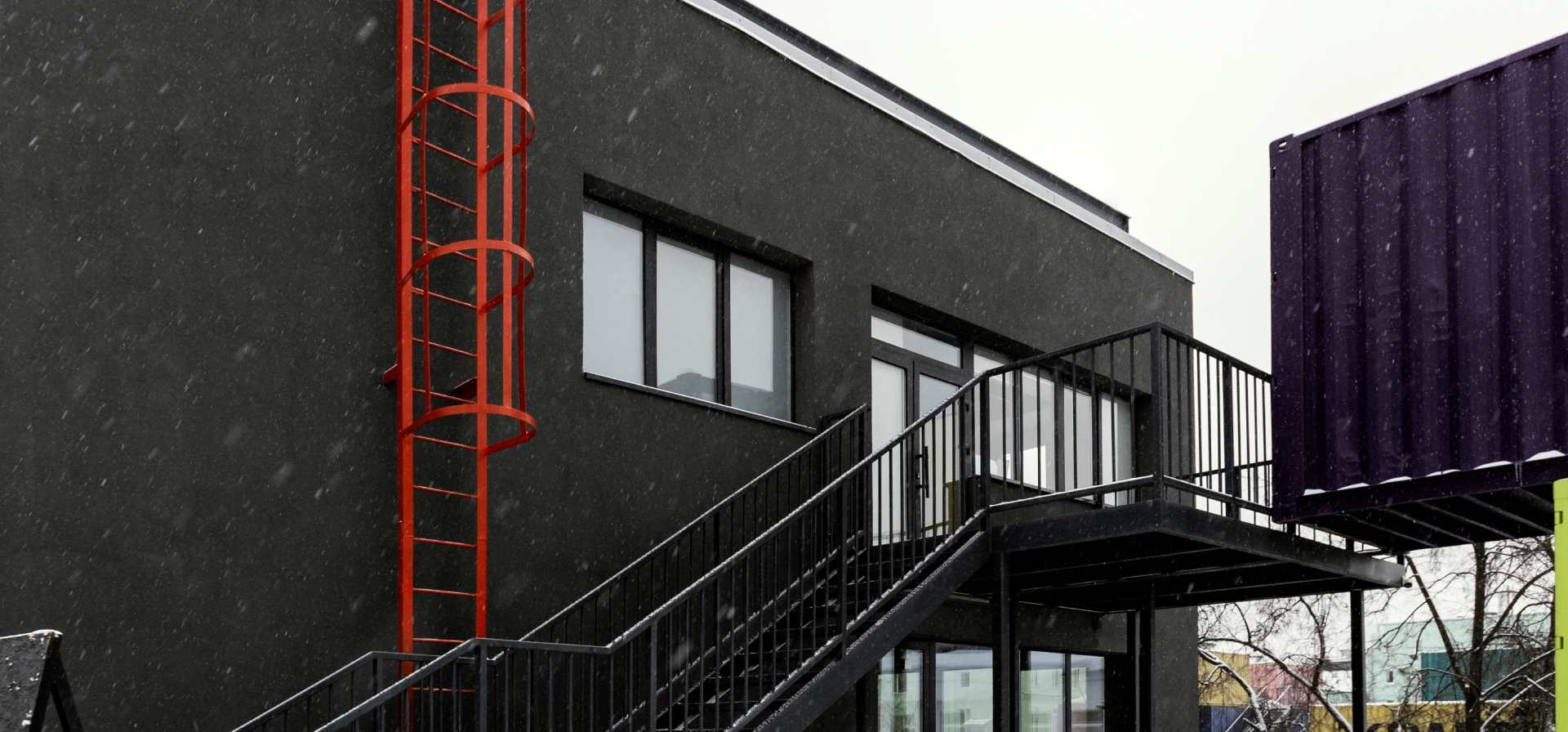 A modular building structure with black walls and emergency ladder.