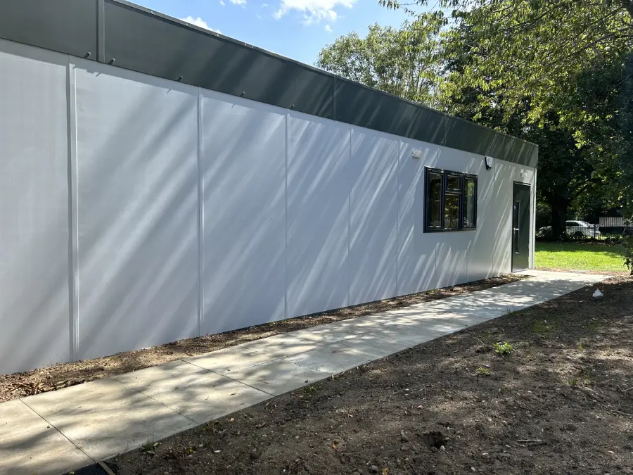 Photo of a modular building, cube shaped with grey wall